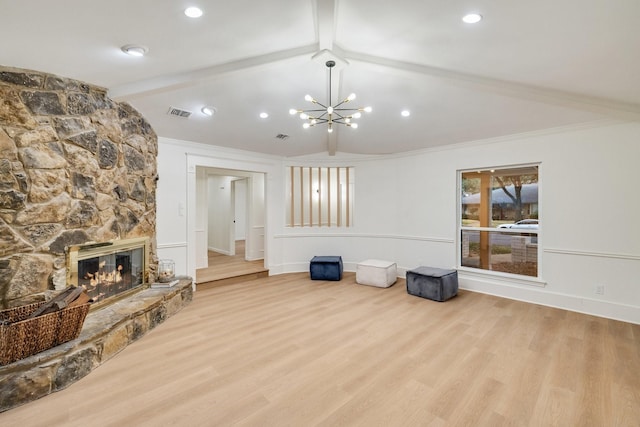 living area featuring lofted ceiling with beams, light wood finished floors, and a stone fireplace