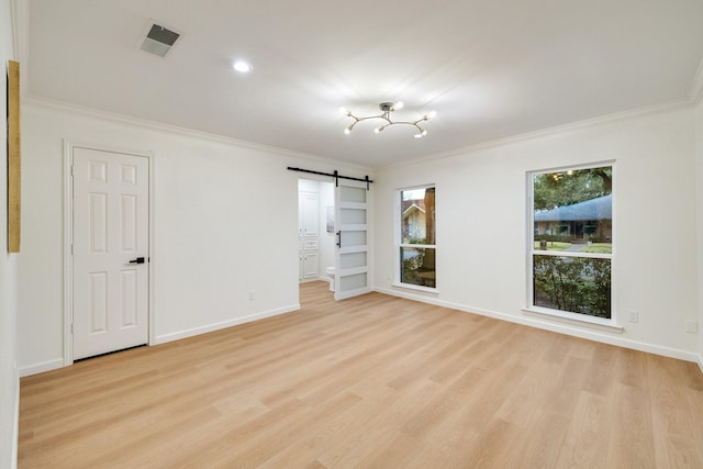 empty room featuring a barn door, visible vents, and ornamental molding