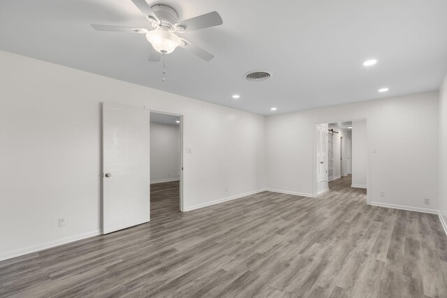 laundry area featuring a barn door, baseboards, stacked washer and dryer, and wood finished floors