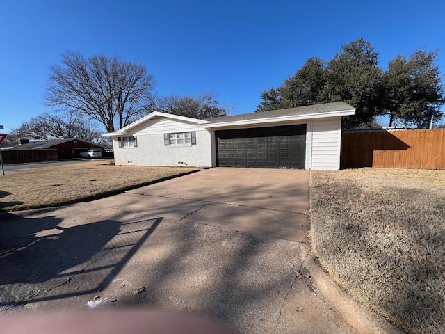 exterior space featuring an attached garage, concrete driveway, and fence