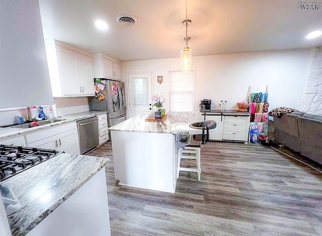 kitchen with white cabinets, wood finished floors, visible vents, and stainless steel appliances