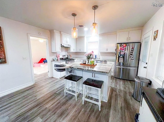 kitchen with under cabinet range hood, white cabinets, stainless steel appliances, and wood finished floors