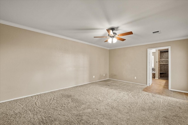 empty room featuring ceiling fan, light colored carpet, visible vents, baseboards, and ornamental molding