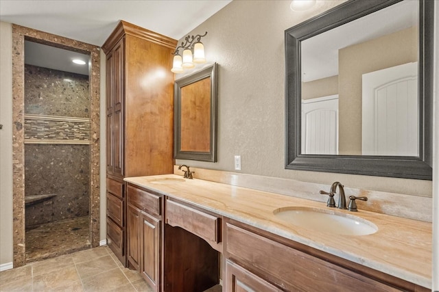 bathroom with double vanity, a tile shower, a sink, and a textured wall