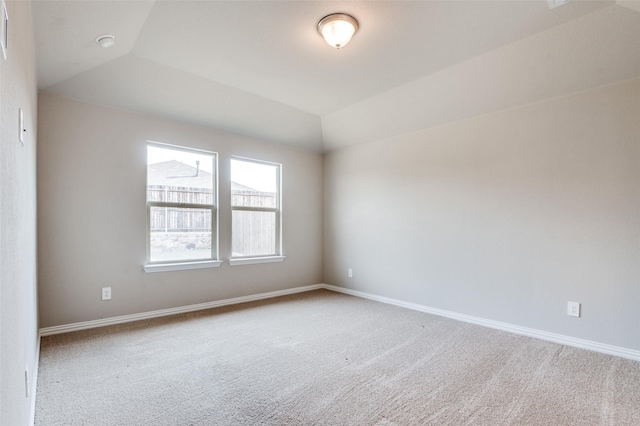 empty room with carpet floors, baseboards, and vaulted ceiling