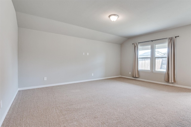 empty room featuring lofted ceiling, carpet floors, and baseboards