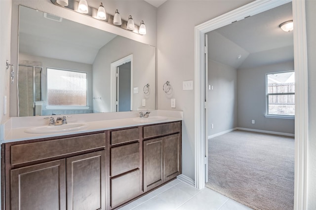 bathroom featuring double vanity, lofted ceiling, visible vents, a sink, and tile patterned flooring