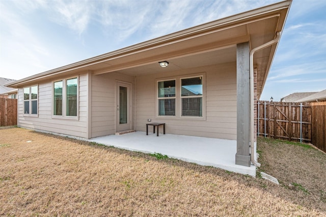 back of property with a patio, a yard, and fence