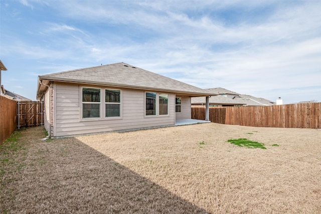 back of property featuring a shingled roof, a patio area, and a fenced backyard