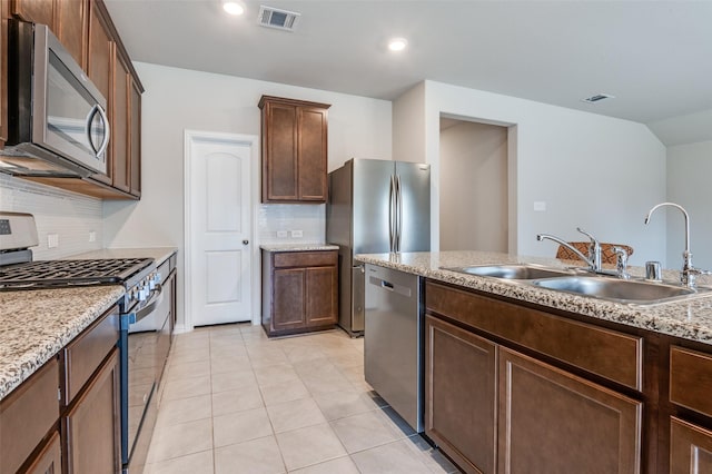 kitchen with tasteful backsplash, visible vents, light stone counters, stainless steel appliances, and a sink