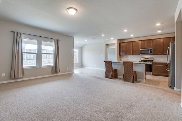 kitchen featuring open floor plan, appliances with stainless steel finishes, light colored carpet, and a center island