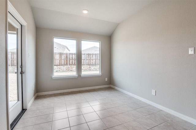 unfurnished room featuring a wealth of natural light, vaulted ceiling, and baseboards