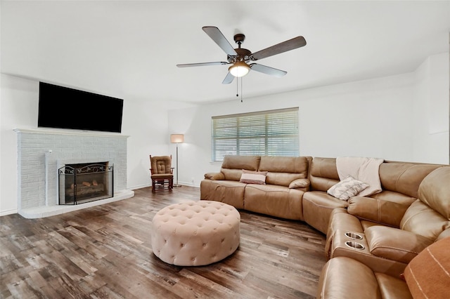 living room with ceiling fan, a fireplace, wood finished floors, and baseboards