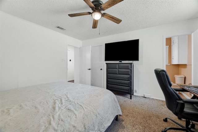 carpeted bedroom featuring a textured ceiling, baseboards, visible vents, and a ceiling fan