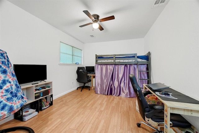 bedroom featuring a ceiling fan, visible vents, baseboards, and wood finished floors