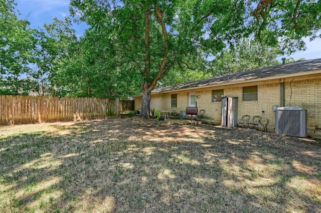 view of yard featuring central AC and fence