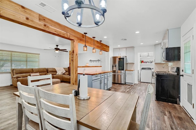 dining area featuring recessed lighting, visible vents, beamed ceiling, wood finished floors, and ceiling fan with notable chandelier