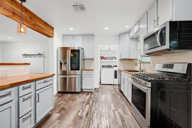 kitchen featuring decorative light fixtures, butcher block counters, visible vents, appliances with stainless steel finishes, and a sink