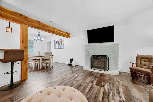 living area featuring visible vents, baseboards, wood finished floors, a fireplace, and beam ceiling