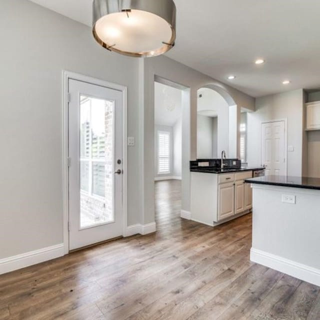 kitchen featuring baseboards, recessed lighting, dark countertops, and light wood-style floors