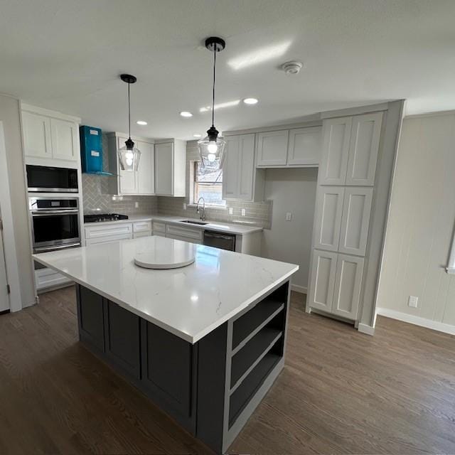 kitchen featuring tasteful backsplash, wall chimney exhaust hood, appliances with stainless steel finishes, dark wood-type flooring, and a sink