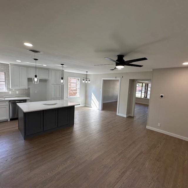 kitchen featuring dark wood-style flooring, light countertops, open floor plan, white cabinets, and dishwasher