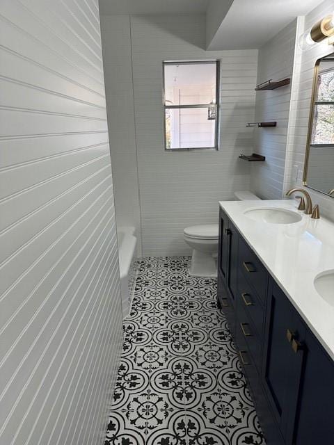 full bathroom with a sink, double vanity, tile patterned flooring, and toilet