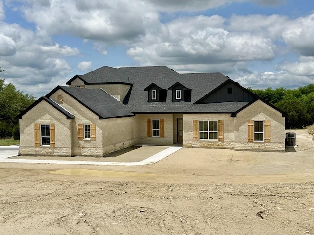 1045 Woodland Rd, Weatherford, TX 76088 - view of front facade featuring brick siding, board and batten siding, central AC, and roof with shingles