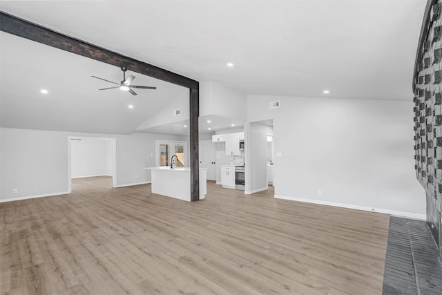 unfurnished living room with visible vents, lofted ceiling with beams, ceiling fan, a sink, and light wood-type flooring