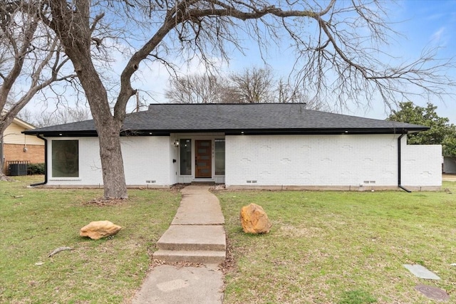 mid-century modern home featuring brick siding, crawl space, a front yard, and a shingled roof