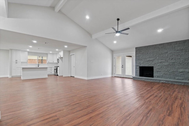 unfurnished living room with ceiling fan, a fireplace, baseboards, and beam ceiling