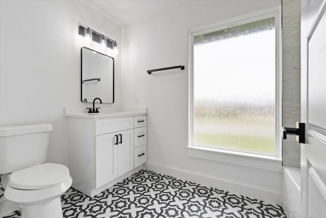 bathroom with toilet, tile patterned floors, baseboards, and vanity