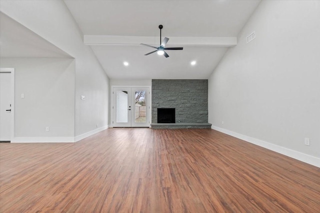 unfurnished living room featuring baseboards, visible vents, lofted ceiling with beams, wood finished floors, and a fireplace