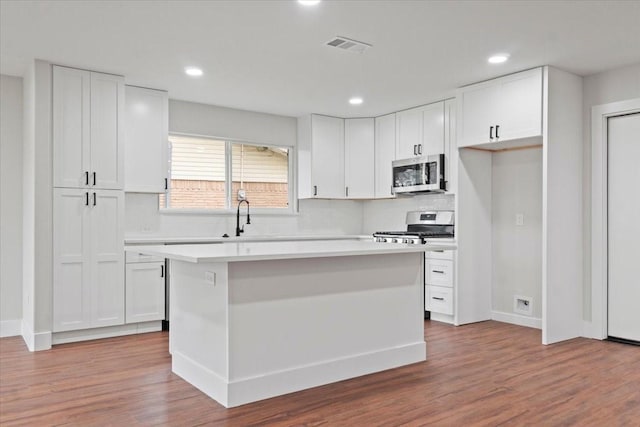 kitchen with light countertops, appliances with stainless steel finishes, a center island, and white cabinets