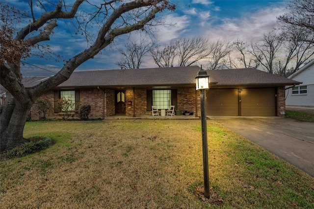 ranch-style house featuring brick siding, a yard, a shingled roof, concrete driveway, and an attached garage