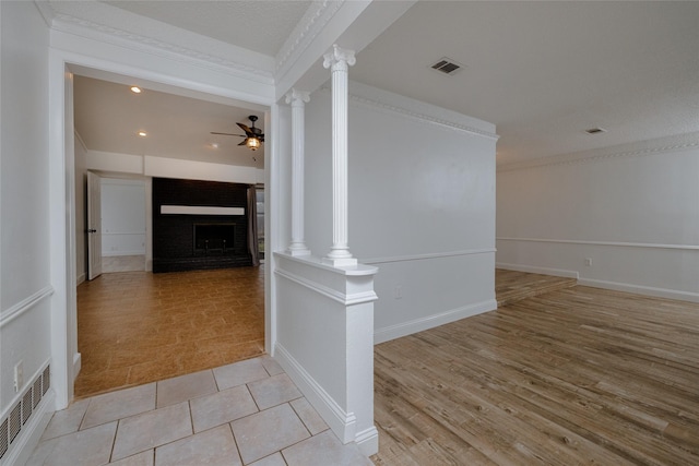 corridor featuring light wood-style floors, decorative columns, visible vents, and ornamental molding