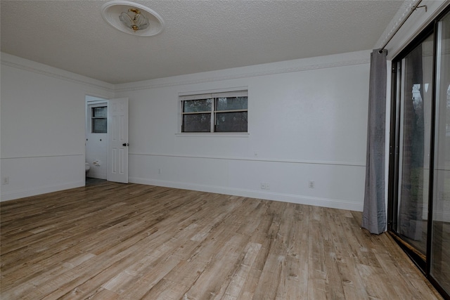 unfurnished room featuring light wood finished floors, baseboards, and a textured ceiling