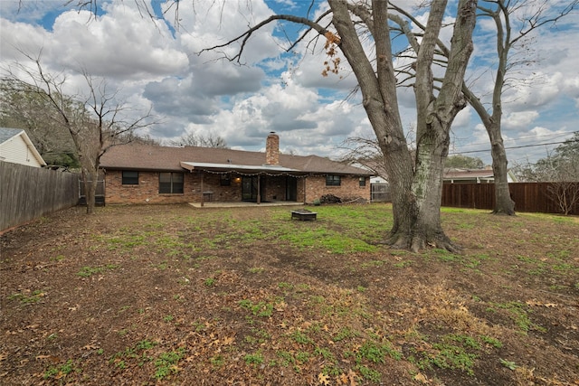 rear view of house with a fenced backyard, a chimney, a patio, and brick siding