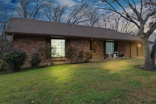 ranch-style home featuring roof with shingles, brick siding, and a front lawn