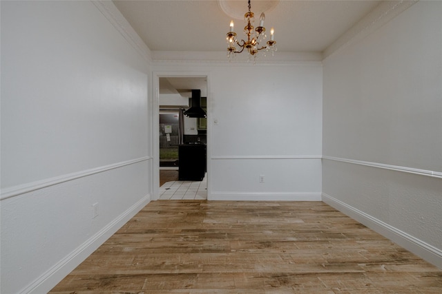 unfurnished dining area with baseboards, an inviting chandelier, and light wood-style floors