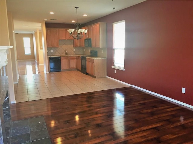 kitchen with tasteful backsplash, a chandelier, light wood-style floors, and black appliances