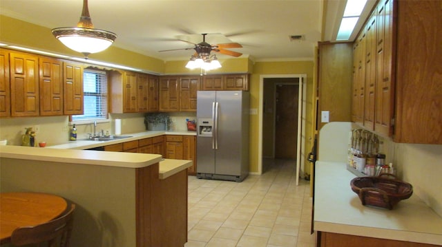 kitchen featuring pendant lighting, stainless steel refrigerator with ice dispenser, light countertops, a sink, and a peninsula