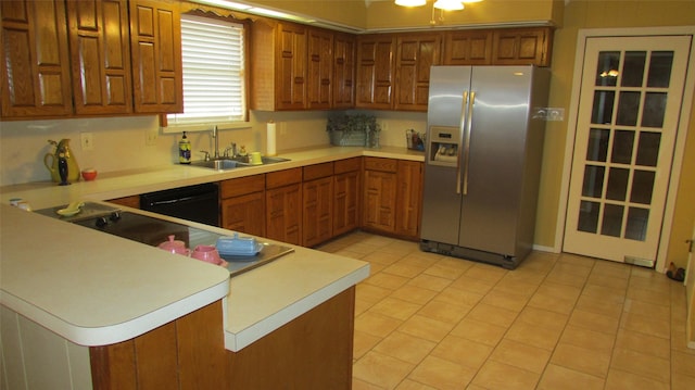 kitchen featuring brown cabinets, stainless steel refrigerator with ice dispenser, light countertops, a sink, and a peninsula