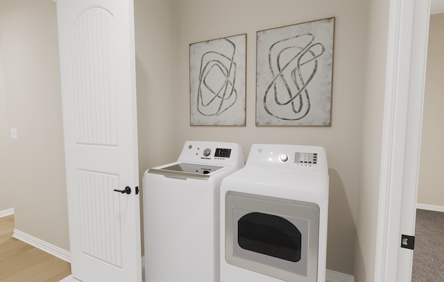 washroom featuring baseboards, wood finished floors, and washing machine and clothes dryer