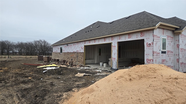 exterior space with a garage, a shingled roof, and brick siding