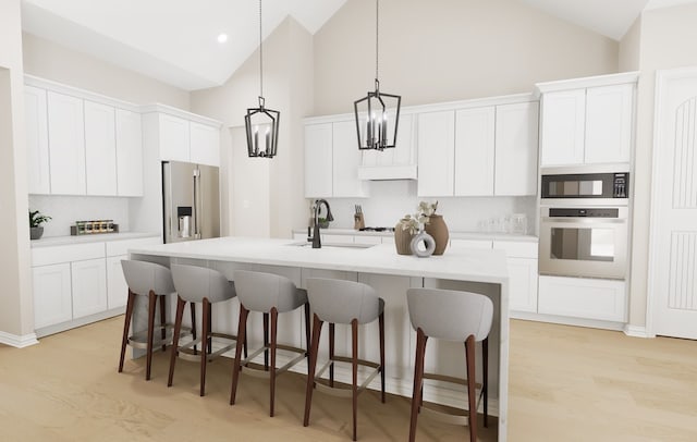 kitchen with wall oven, stainless steel fridge, a center island with sink, light countertops, and white cabinetry