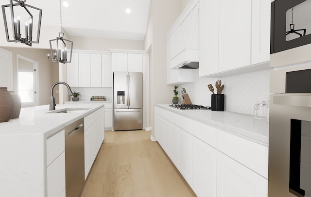 kitchen with appliances with stainless steel finishes, decorative light fixtures, a sink, white cabinetry, and a notable chandelier