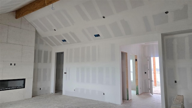 unfurnished living room with high vaulted ceiling, beamed ceiling, and a glass covered fireplace