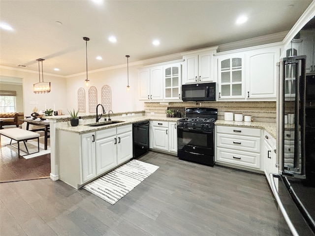 kitchen with glass insert cabinets, decorative light fixtures, a peninsula, black appliances, and a sink