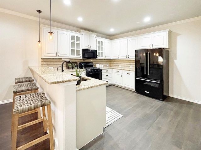 kitchen with glass insert cabinets, hanging light fixtures, a peninsula, black appliances, and white cabinetry